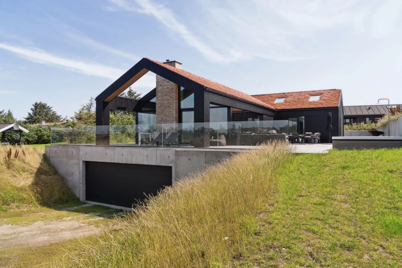 Villa Tornmark set udefra med sort træfacade, grønt sedumtag og garage integreret i terræn