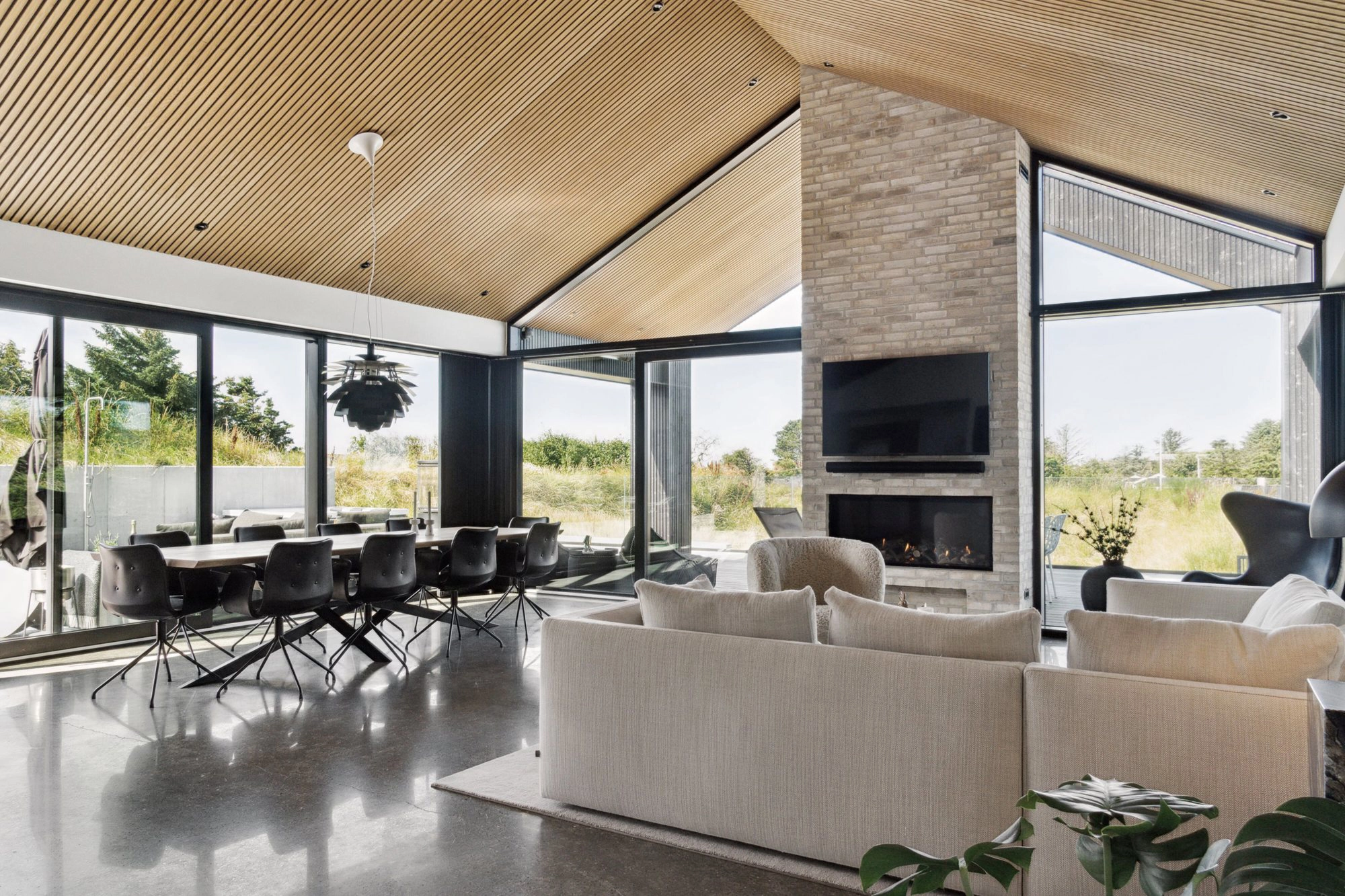 Opholdsrum i Villa Tornmark med pejs, spiseområde og store glaspartier mod naturen