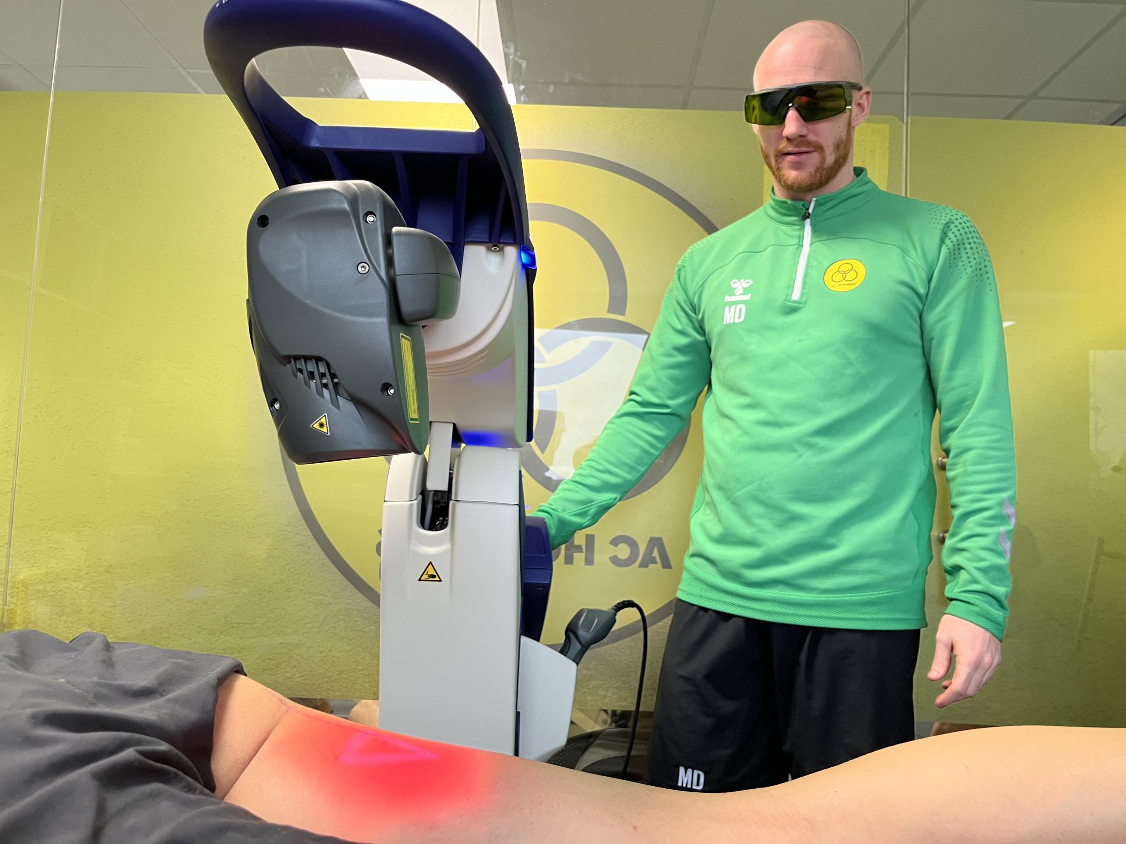 Fysioterapeut behandler fodboldspiller med en sportsskade med laserterapi