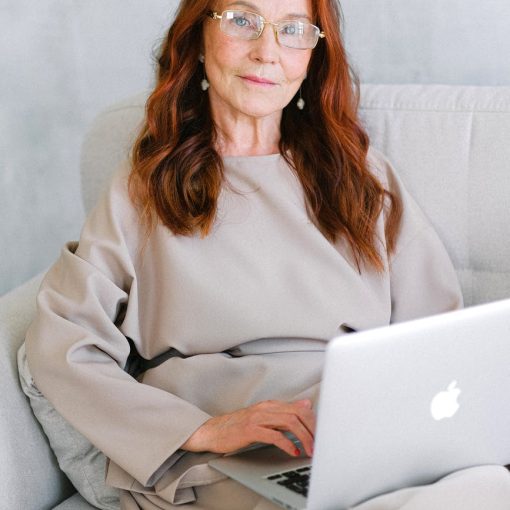 charming elderly woman using laptop on sofa