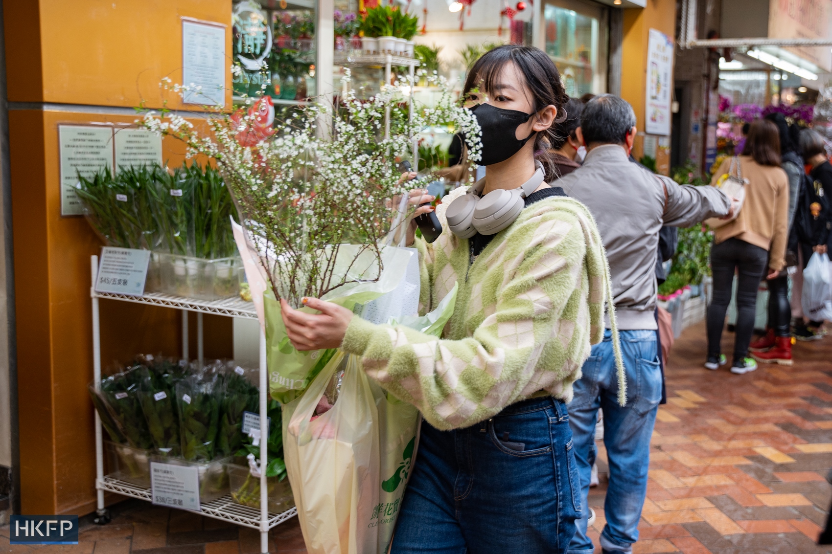 A woman carries a plant through the flower market in Mong Kok, Hong Kong, in January 2023. Photo: Kyle Lam/HKFP. 