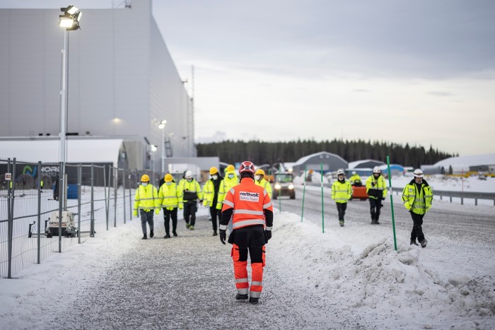 Exterior of the factory with workers in high-vis clothing walking past in the snow