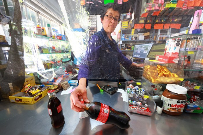 A store cashier holding a bottle of Coca-Cola