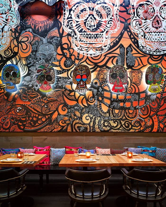 Red and orange Day of the Dead decor on the wall behind tables in El Catrin restaurant