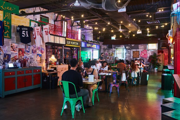 Diners eating at tables flanked by east Asian food stalls in Superfresh