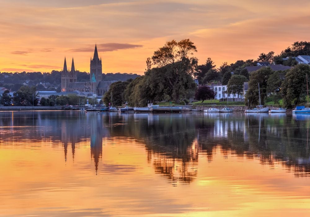 A view of a river at sunset from Malpas with Truro Cathedral in the background.