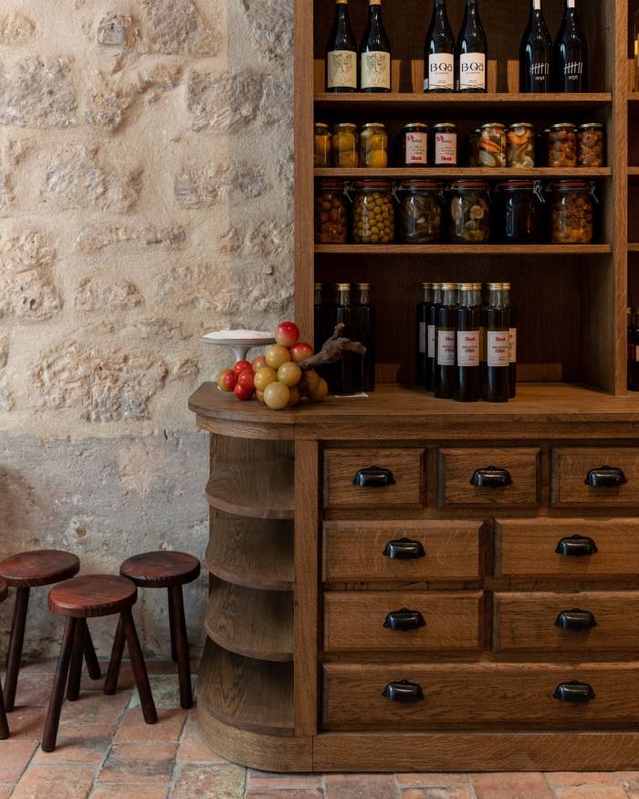 Jars of olives and pickles and glass bottles on a rustic wooden cabinet in Shosh restaurant 