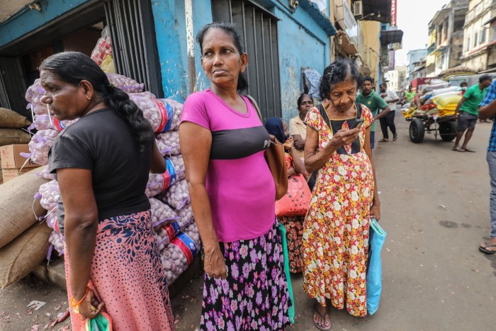 Women stand in the street at the wholesale market in Colombo