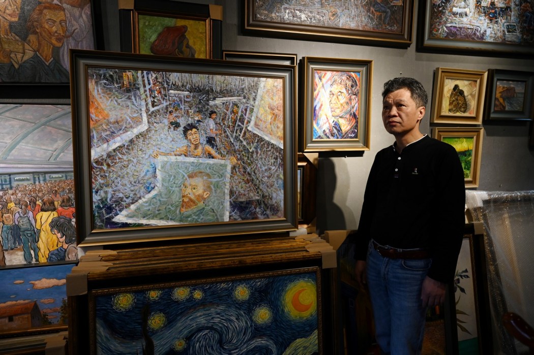 Artist Zhao Xiaoyong standing next to his paintings at Dafen village, in Shenzhen, in China's southern Guangdong province, on February 19, 2023. Photo: Greg Baker/AFP.