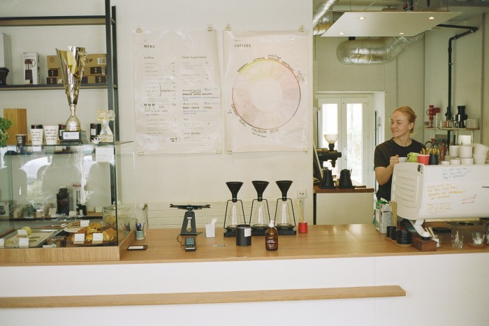 The counter at Mame, with pastries and trophies on a glass shelf and Dominika Kowalska at a large white coffee machine