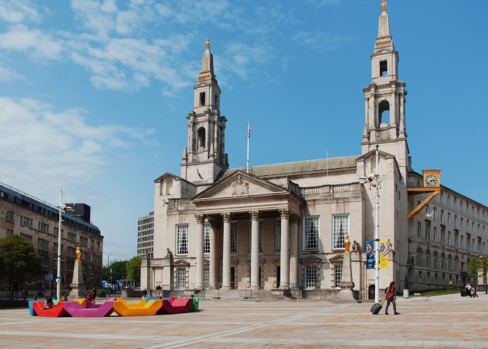 A grand public building of pale grey stone with a central portico and two spires