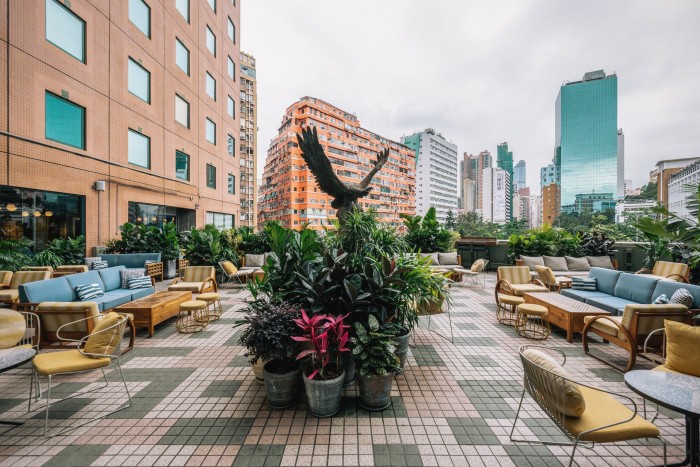 The rooftop terrace at Terrible Baby bar, with plants and a sculpture of an eagle in its centre, looking over Hong Kong high-rises and skyscrapers