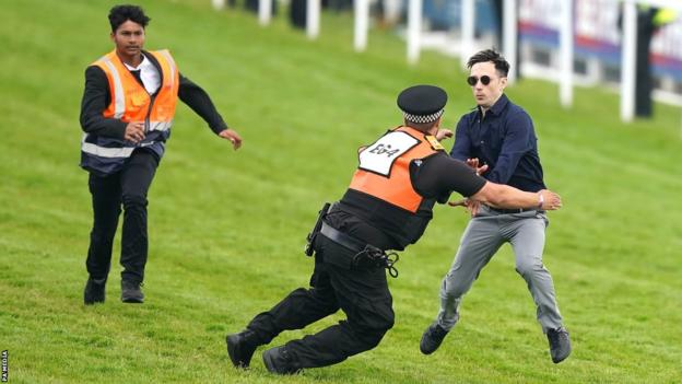 A protestor is tackled by police and stewards during the Derby at Epsom Downs Racecourse, Epsom