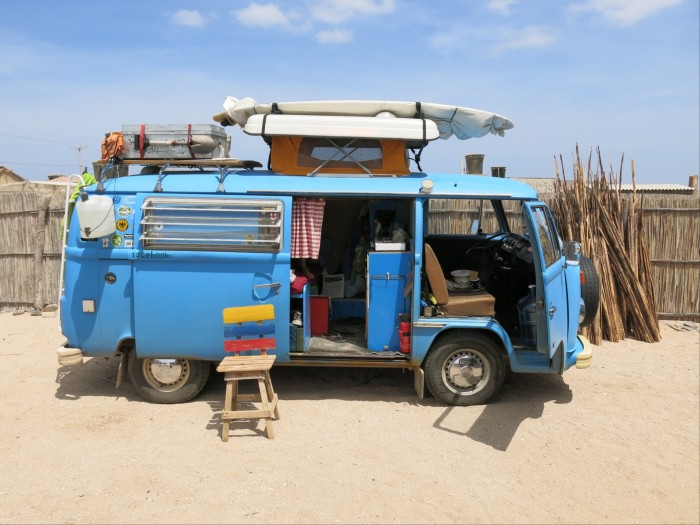 A blue camper van on the beach