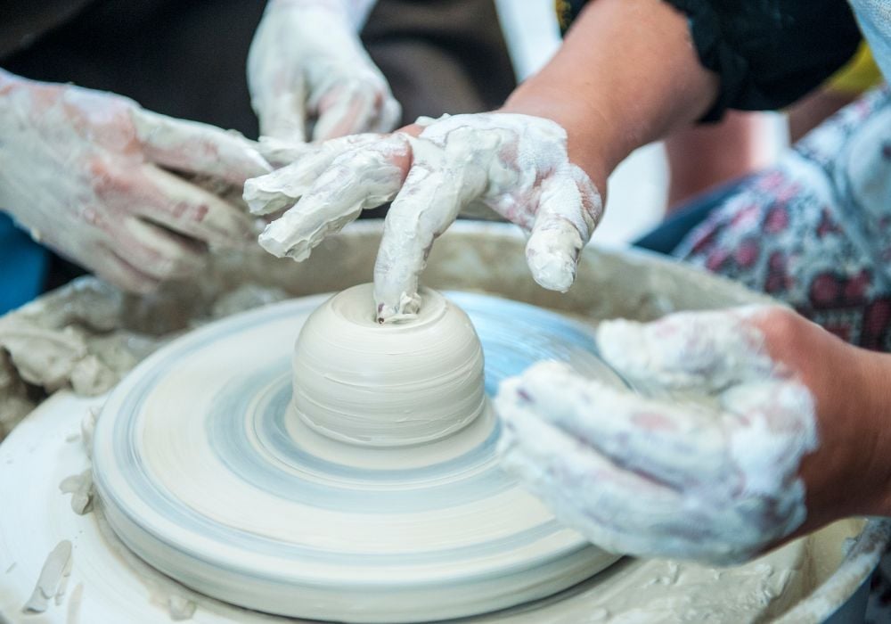 The potter makes pottery dishes on potter's wheel.