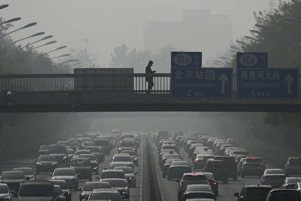 Pedestrians walk on an overpass as traffic snarls amid haze from air pollution in Beijing on November 1, 2023. Photo: Pedro Pardo/AFP.