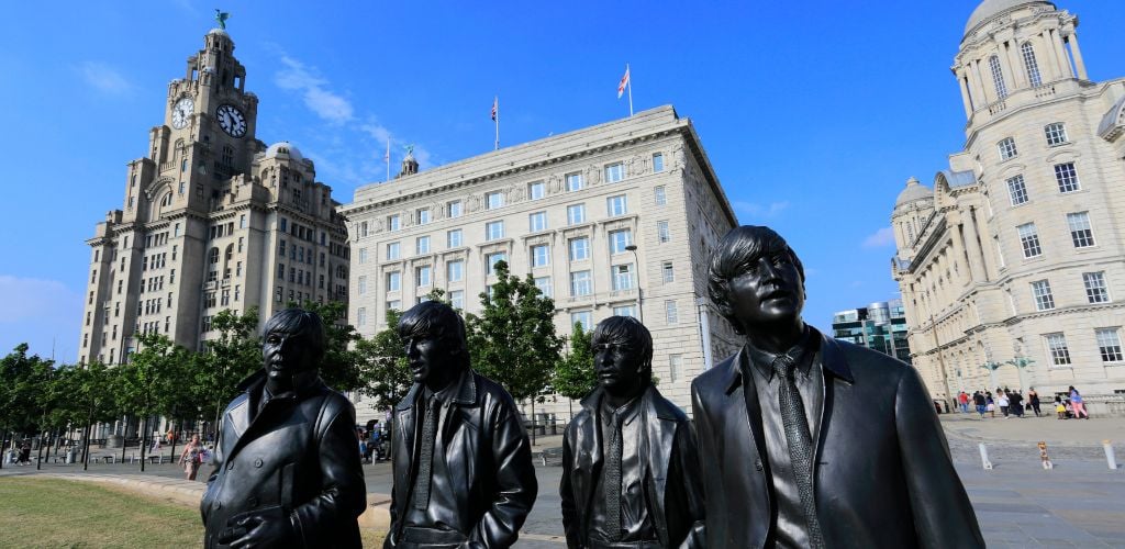 The Beatles Statues on the city surrounded by building. 