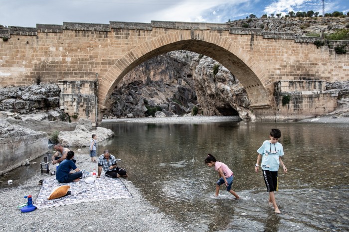 Children play in a shallow river beneath a humpback bridge built by the Romans