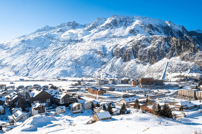 An aerial photograph of Andermatt, a traditional Swiss Alpine village surrounded by snowy peaks