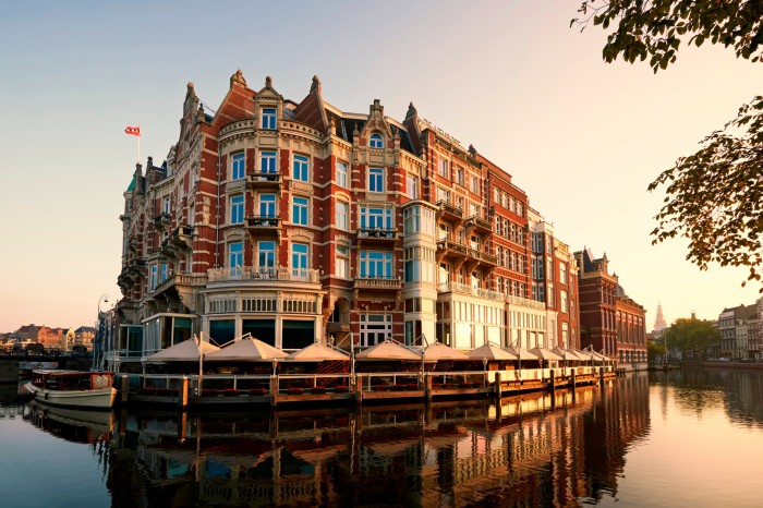 The facade of Amsterdam’s De L’Europe hotel: a historic red-brick building at the side of a canal