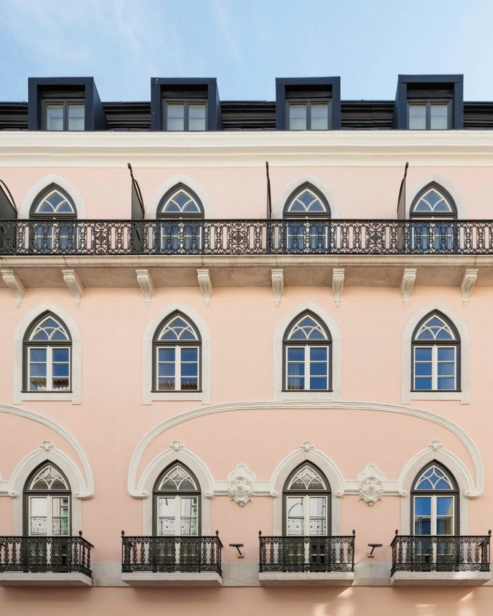 Rows of arch-shaped windows in the pink 19th-century facade of Lisbon’s The Ivens hotel