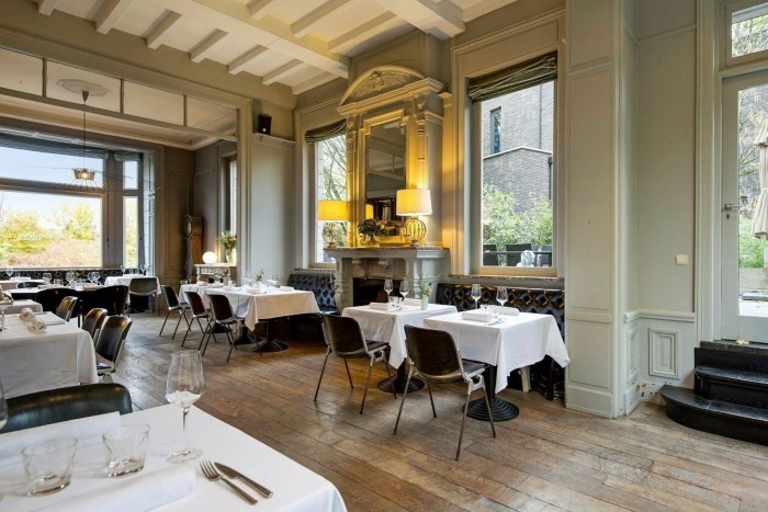 The airy, high-ceilinged restaurant in Lille’s Les Toquées hotel, with tables and chairs on parquet flooring and leather banquettes around the wall