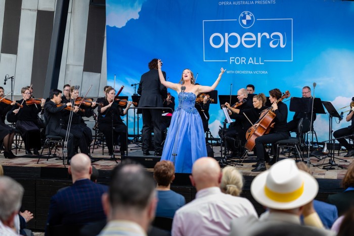 A female opera singer in a blue dress, on stage in front of an orchestra, at last year’s BMW Opera for All