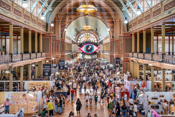 Aerial shot of the Big Design Market: crowds of people browsing rows of stalls beneath the glass-ceilinged Royal Exhibition Building 