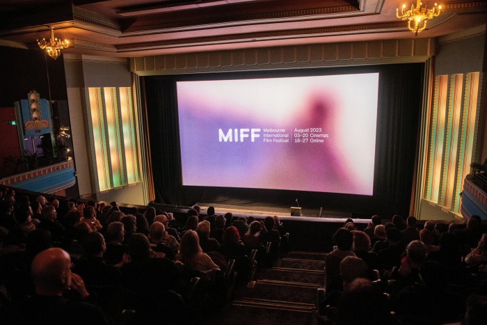 An audience in a cinema watching a screen that reads ‘MIFF 2023’