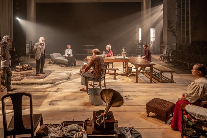 Actors in Crow’s Theatre’s production of ‘Uncle Vanya’ sitting on chairs or standing on a large stage
