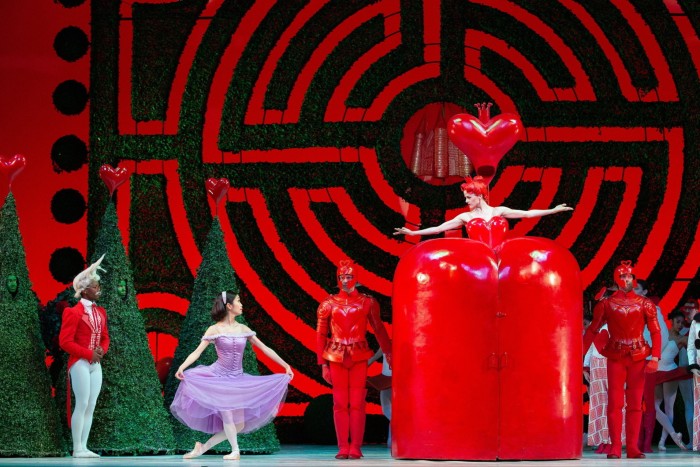 A scene from the National Ballet of Canada’s production of ‘Alice’s Adventures in Wonderland’, with the Queen of Hearts, Alice and the White Rabbit against a backdrop of a circular red maze 