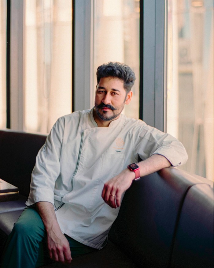 Executive chef Tejas Sovani – a moustachioed man in chef’s whites – sitting on a banquette by a large window in Spice Lab Tokyo