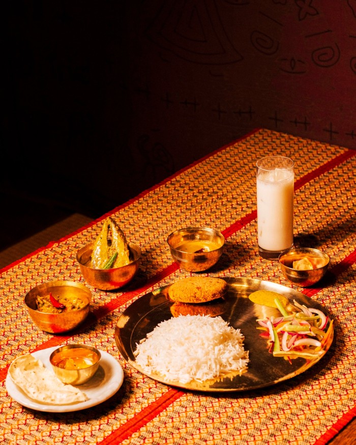 A full Bengali meal on a rattan-topped table at Puja 