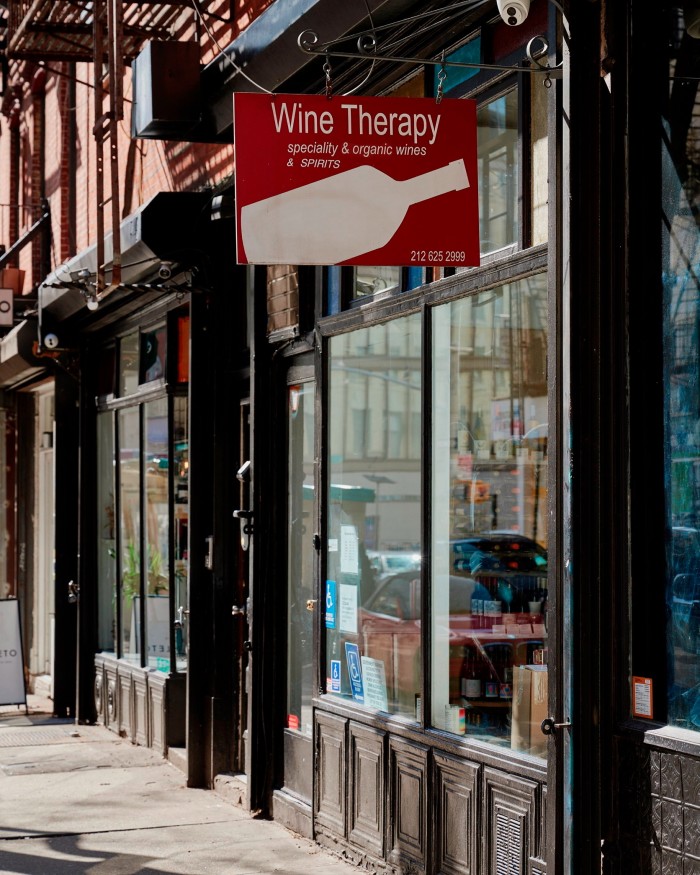 The facade of Wine Therapy, with a red sign with a white wine bottle on it hanging above the window