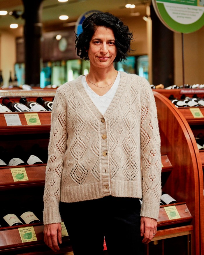 Lorena Asencios, Astor’s head wine-buyer, standing in front of shelves on which bottles of wine are lying horizontally in rows