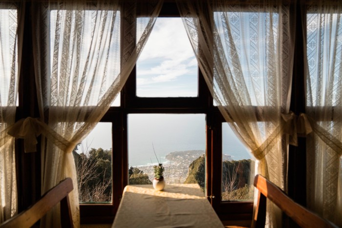 A view through a curtained window to the sea below
