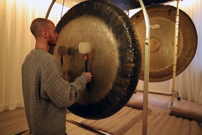 Sound-artist Leo Cosendai tapping a large gong with two wands with cushioned heads at The Other House members’ club  