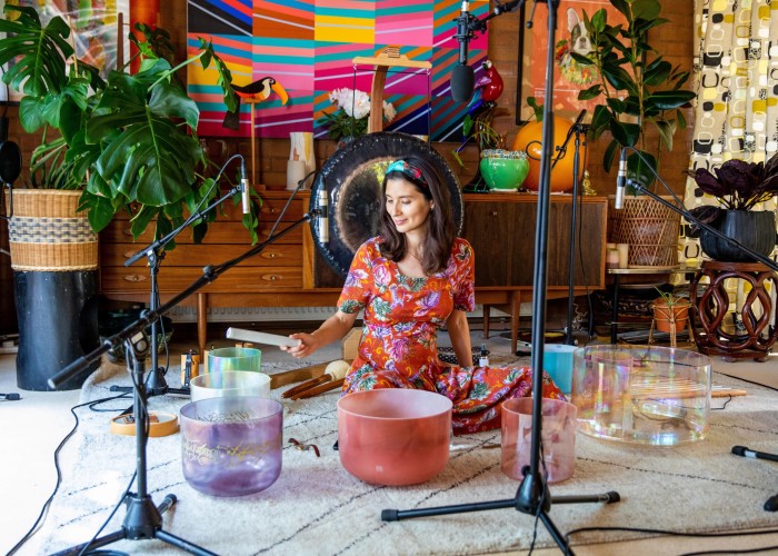 Jasmine Hemsley recording one of her sound-bath sessions, tapping one of an array of colourful singing bowls while surrounded by microphones