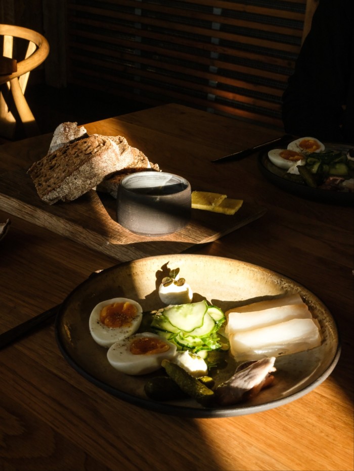 A rustic round plate of food, including split hard-boiled eggs and cucumber salad