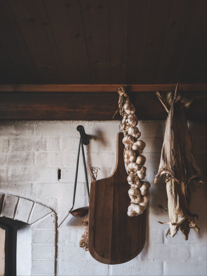 The whitewashed wall of an old-style kitchen with a bunch of hanging dried garlic