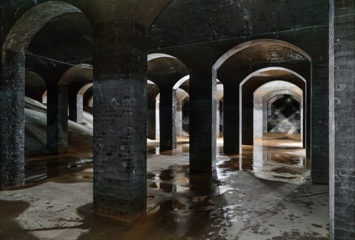 Dimly lit grey-brick archways and columns on a concrete floor in Cisternene, Cisternerne, a gallery in a former reservoir beneath Copenhagen
