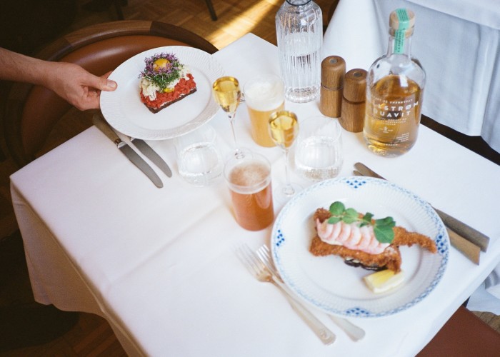 Smørrebrøds at Møntergade restaurant: beef tartare and fried plaice with mayo and shrimps, on two individual white plates on a set table