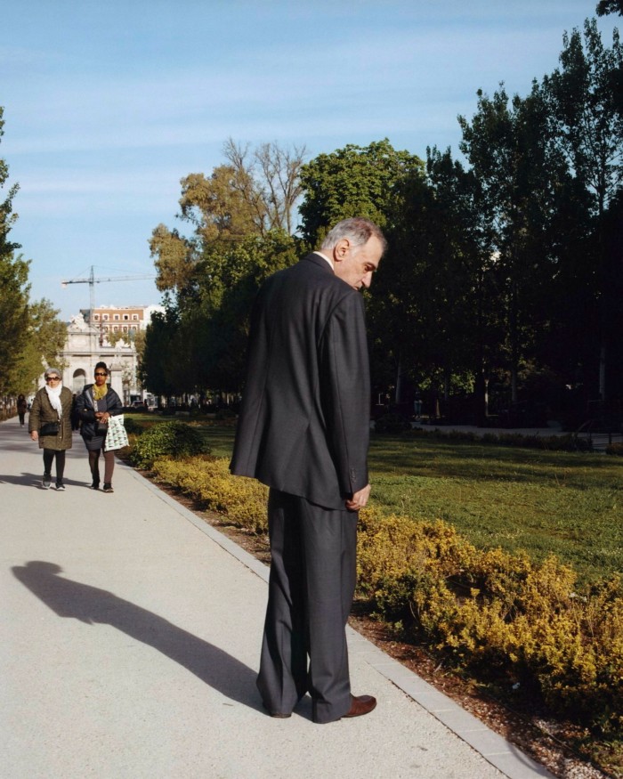 A man in a black suit looking down at a floral border