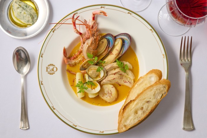 Seafood in a rouille sauce, with slices of bread on the side of the dish 