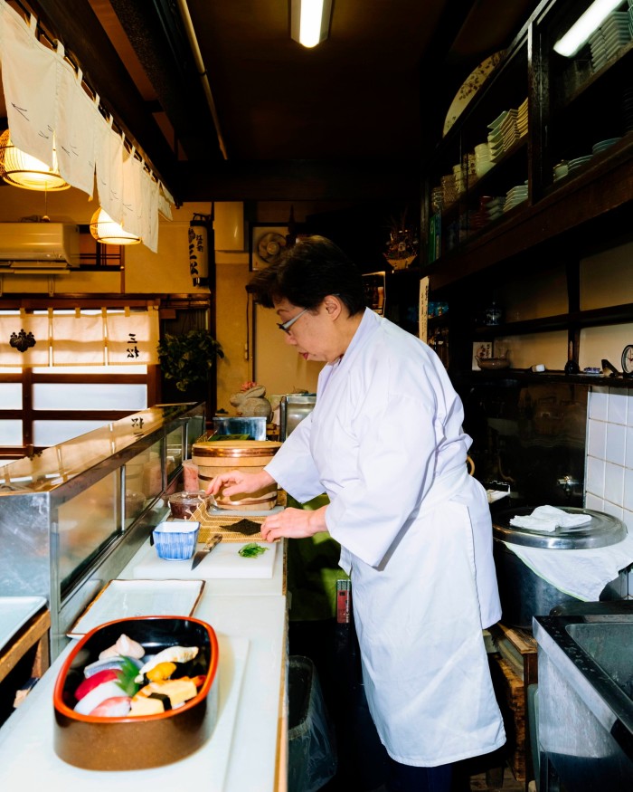 Chef Yukiko Okuzumi in the kitchen of her restaurant, preparing sushi on a counte