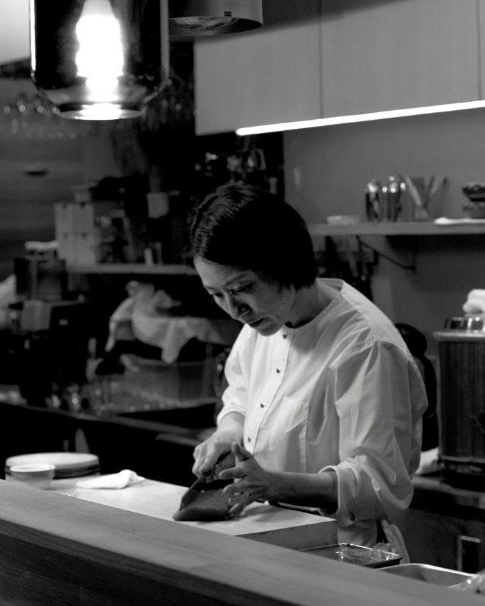 A black and white photograph of chef Yuko Suzuki at work in her restaurant’s kitchen