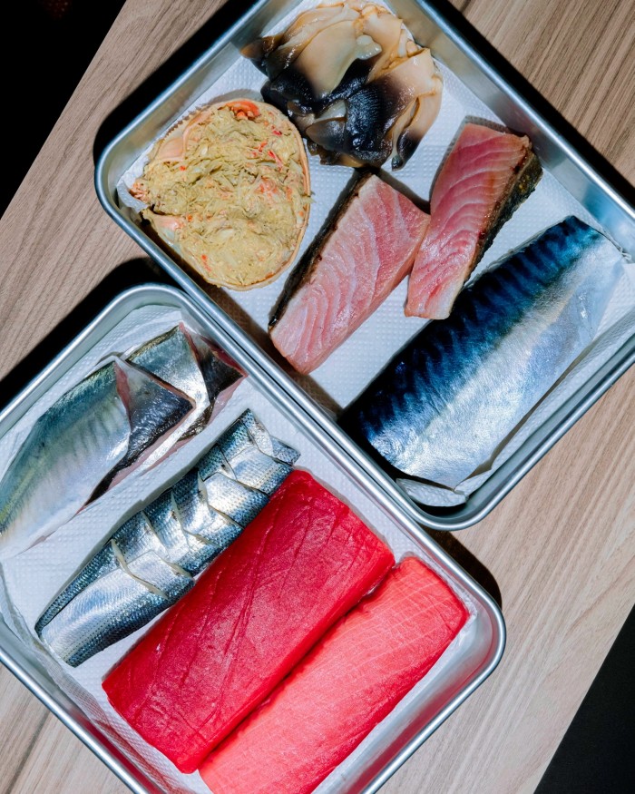 Pieces of fresh fish in silver rectangular trays at Sushi Yuko