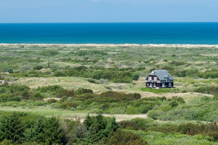 One lone house nestled in the landscape with the sea in the background