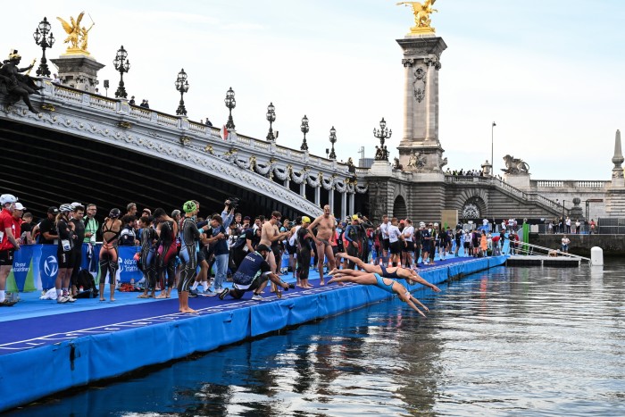 Athletes dive into the waters of the River Seine at the Alexander III Bridge ahead of triathlon test races in August 2023