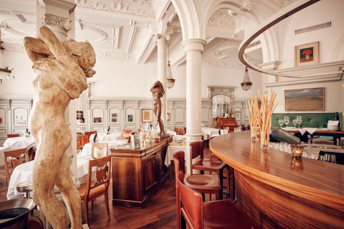 The interior of Conti, an Italian restaurant in Zürich, with white marble columns, archways and statues of semi-naked women